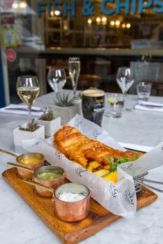 fish and chips served on a wooden platter in front of a storefront window