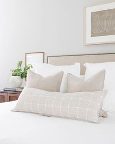 a bed with white sheets and pillows in a bedroom