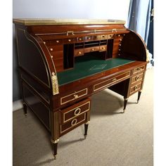 an antique desk with green top and gold trim