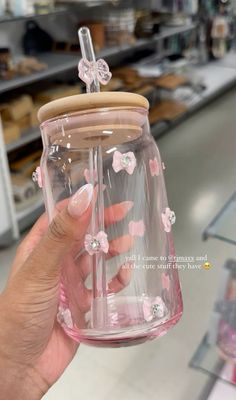 a person holding up a pink glass jar with flowers on the inside and a wooden lid