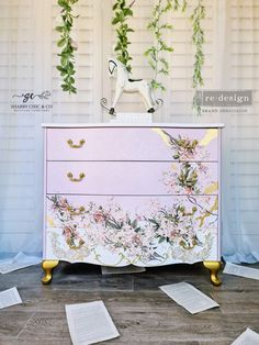 a dresser with flowers painted on it and some papers scattered around the drawers in front of it