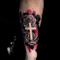 a cross and roses tattoo on the leg