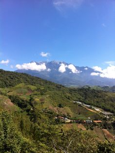 the mountains are covered with green trees and clouds in the distance, as seen from an overlook point