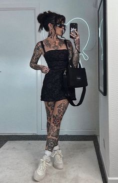 a woman with tattoos taking a selfie in the mirror while holding a cell phone