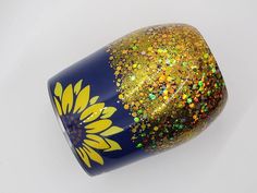 a blue and yellow vase with gold flecks on it's sides, sitting on a white surface