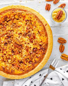 an overhead view of a pizza on a table with pecans and other toppings