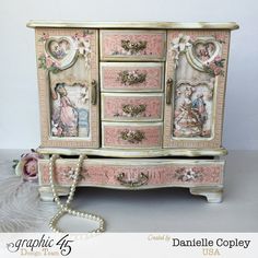 an ornate dresser with pink and white decor on the doors, drawers, and handles