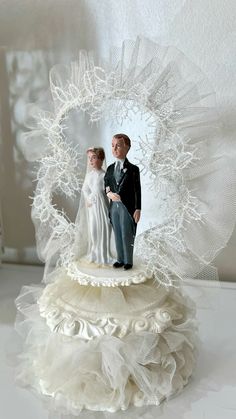 a wedding cake topper with a bride and groom standing in front of a white background