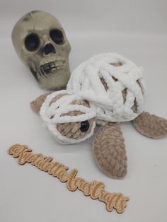 a crocheted turtle with the word congratulations written in front of it next to a fake human skull