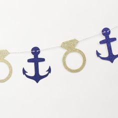 an anchor and ring banner hanging from a string on a white background with blue glitter