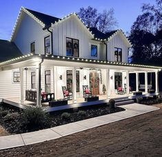 a white house with christmas lights on it's windows and porches at night