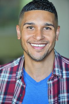 a man with a goatee smiles at the camera while wearing a red and blue shirt