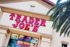 a trader joe's store front with palm tree in the foreground and sign above it