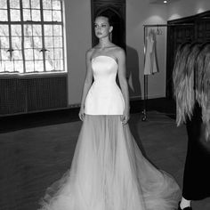 a woman standing in front of a dress on display