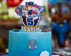 a blue cake with paw patrol characters on it's top and the number five