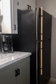 a black refrigerator freezer sitting inside of a kitchen next to a white counter top