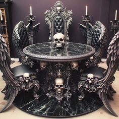 a dining room table with skulls and wings on it's legs, surrounded by candles