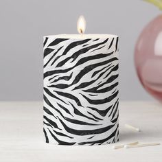 a zebra print candle holder next to a pink vase