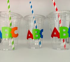 three plastic cups with different colored straws in them and the letters abc are cut out