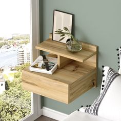 a wooden shelf with two drawers and a plant on it in front of a window