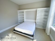 an empty bedroom with a bed, bookcases and window in the corner is shown