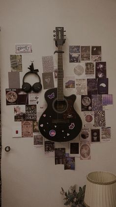 a guitar mounted to the wall with many pictures on it and a lamp next to it