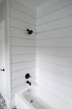 a white bath tub sitting next to a black and white tiled floor