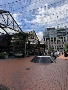 people are walking around in the city with many lights strung above them and buildings on both sides