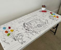 a table with a drawing on it in front of a white wall and some toys