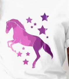 a woman wearing a white t - shirt with purple horse and stars on it