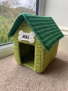 a crocheted green dog house with a bone on the top and a name tag that says max