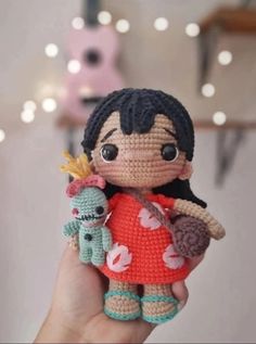 a small crocheted doll holding a stuffed animal in it's right hand