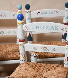 two wooden chairs decorated with colorful designs and name stick decorations on the back of them