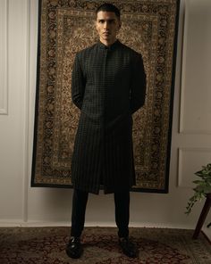 This stunning black sherwani epitomizes geometric sharpness, boasting intricate tonal embroidery on a silk base. Each stitch is meticulously handcrafted to perfection, creating an illusion of fabric that mesmerizes the eye. With its impeccable craftsmanship and attention to detail, this sherwani stands as a true testament to sophistication and style, making it the ideal choice for any formal occasion or cultural celebration.From Jigar & Nikita's Summer Romance collection. DELIVERY TIMEPlease all Elegant Black Kurta With Naqshi Detailing, Elegant Black Kurta With Naqshi, Formal Black Sherwani With Naqshi Detailing, Black Long Sleeve Traditional Wear For Semi-formal Occasions, Black Long Sleeve Traditional Semi-formal Wear, Ceremonial Black Kurta With Naqshi Detailing, Ceremonial Black Kurta With Naqshi, Black Long Kurta For Formal Occasions, Long Black Kurta For Formal Occasions