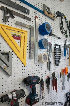 there are many tools on the pegboard and one is hanging from the wall above it