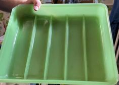 a person holding a green tray in their hand