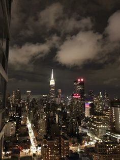 the city skyline is lit up at night with skyscrapers in the foreground and clouds in the background