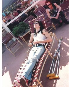 two women sitting on top of chairs in front of a building with mirrors reflecting them