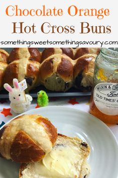 hot cross buns on a plate next to a jar of orange marmalade