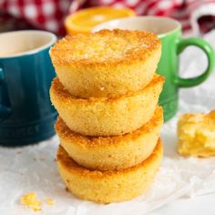 a stack of sugary donuts sitting next to a cup of coffee on top of a table