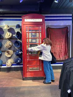 a woman leaning against a red phone booth