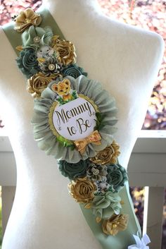 a white mannequin wearing a green sash with flowers on it