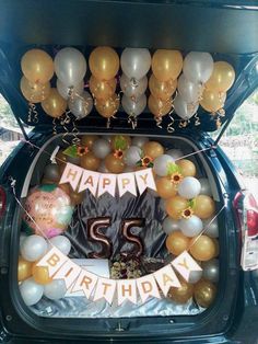 the trunk of a car with balloons and decorations