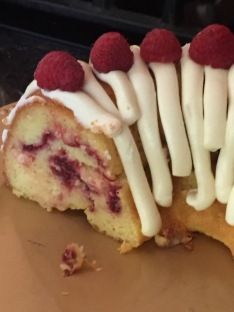 a piece of cake with white icing and raspberries sitting on top of it