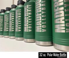 a row of green water bottles sitting on top of a white counter