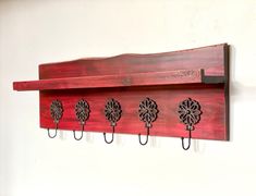 a wooden coat rack with four metal hooks on it's sides, hanging from the wall