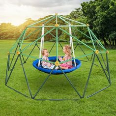 two children are sitting in a large metal structure on the grass, and one child is playing inside