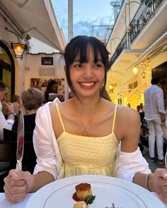 a woman sitting in front of a white plate with food on it