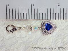 "Petite Something Blue Swarovski Heart Charm - This small handmade keepsake charm is made with a gorgeous 14mm heart pendant in a deep sapphire blue cubic zirconia with surrounding clear CZ stones. It also has a silver-plated lobster clasp, and two sparkling Swarovski bicone crystal beads separated by a silver and crystal rondelle spacer. It's very sparkly! THIS CHARM IS PETITE and measures a total of 2-inches long (including the clasp). You can easily attach it to your wedding bouquet, keepsake Heart Cut Charms Jewelry For Wedding, Blue Heart-shaped Keepsake Jewelry, Blue Heart-shaped Wedding Jewelry, Bouquet Keepsake, Wedding Bouquet Charms, Swarovski Heart, Bridal Accessory, Bouquet Charms, Blue Gift