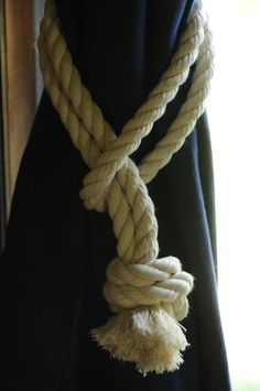 a white rope hanging from the side of a black curtain in front of a window